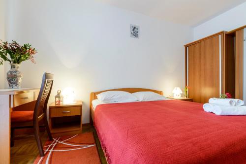 a bedroom with a red bed with a chair and a desk at Oreb Dream Apartments in Koločep