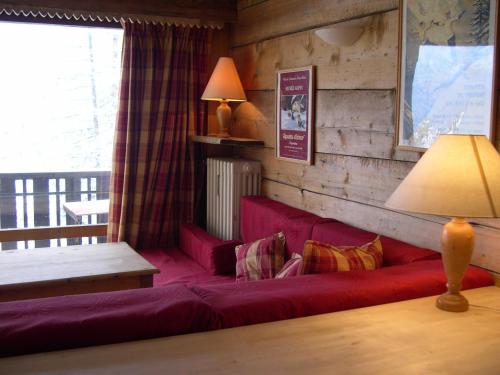 a living room with a red couch with pillows at Studio Les Drus / Studio du Brévent in Chamonix-Mont-Blanc