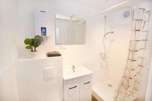een witte badkamer met een wastafel en een douche bij Ferienwohnung BECKENDORF in Losheim