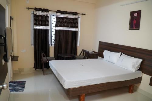 Un dormitorio con una cama grande y una ventana en Hotel Jothi, en Coimbatore