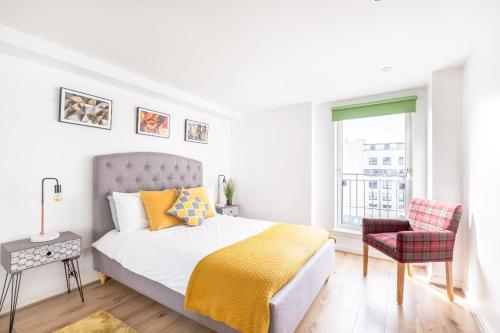 a white bedroom with a bed and a chair at Cosy Apartment in Quiet City-Centre with Car Park in Glasgow