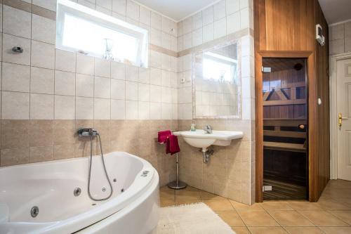 a bathroom with a tub and a sink at Nyirfa Apartmanház Döröske in Döröske