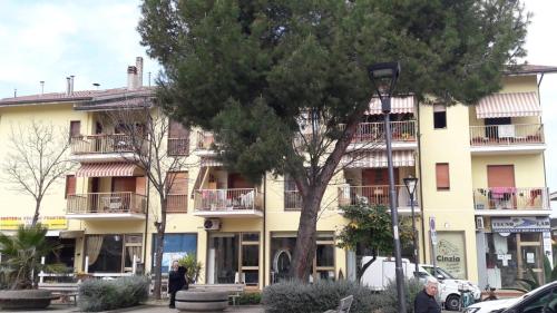 皮內托的住宿－Appartamento da Marco，一座黄色的大建筑,前面有一棵树