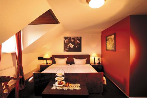 Un dormitorio con una cama y una mesa con comida. en Das Krimihotel en Hillesheim