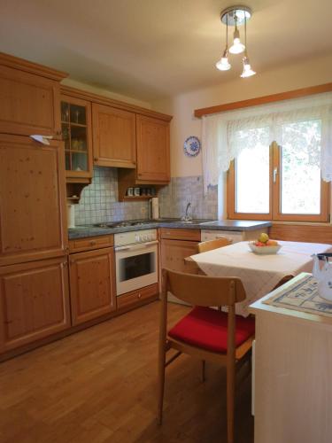 a kitchen with wooden cabinets and a table with a chair at Ferienwohnungen Margreiter in Mitterbach