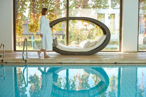 a woman is standing next to a swimming pool at Biohotel Eggensberger in Füssen