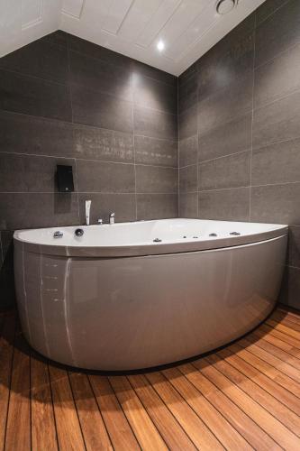 a bath tub in a bathroom with a wooden floor at Dalecarlia Hotel & Spa, BW Premier Collection in Tällberg