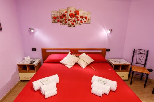 um quarto com uma cama vermelha e toalhas em Rio Launaxi Guest House em Teulada