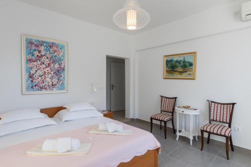 een witte slaapkamer met een bed en 2 stoelen bij Guest House Libertas in Dubrovnik
