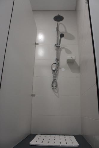 a shower in a bathroom with a white wall at UAU Hostel in Figueira da Foz