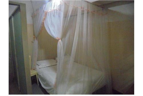 a small bed with white curtains in a room at Hotel Jaffers Nairobi in Nairobi