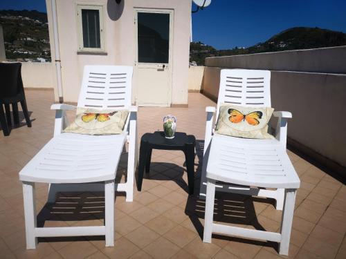 2 sillas blancas con almohadas de mariposa y una mesa en Tenente Amendola 2, en Lipari