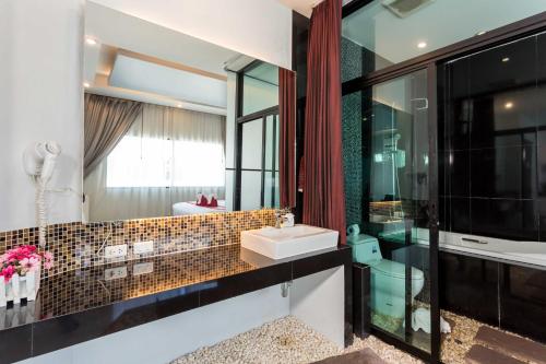 ein Bad mit einem Waschbecken und einem Spiegel in der Unterkunft PJ Patong Resortel in Patong Beach