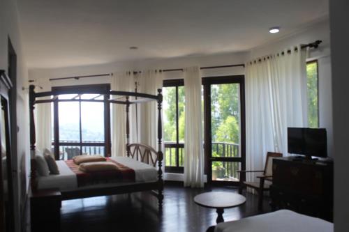 a bedroom with a bed and a balcony with windows at Lawan One Kandy in Kandy