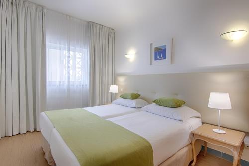 um quarto de hotel com uma cama grande e uma janela em Luna Miramar Club em Albufeira