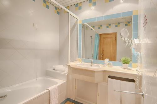 a bathroom with a tub and a sink and a mirror at Luna Miramar Club in Albufeira
