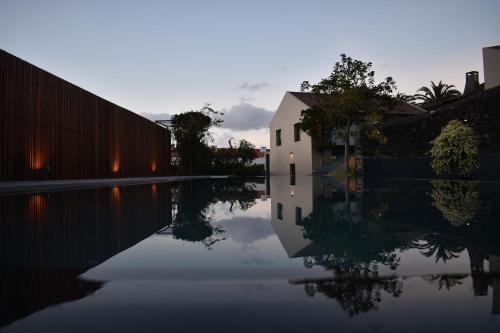 a reflection of a building in a body of water at Volcanic Charming House in Ribeira Grande