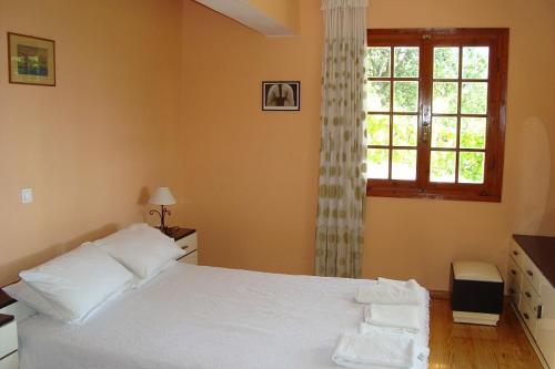 um quarto com uma cama branca e uma janela em Villa's ground floor apartment with 60 qm swimming pool em Palaiokatoúna