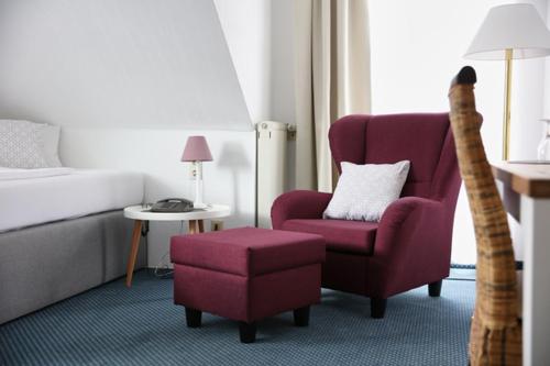 a hotel room with a bed and a chair and a cat arranging a room at Hotel Lammerts in Horn-Bad Meinberg