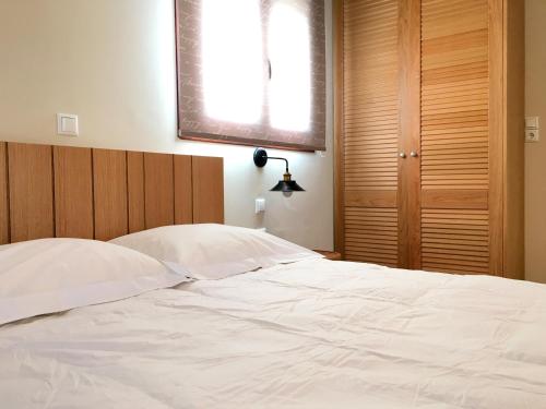 a white bed with a wooden headboard and a window at Aria Monte Villas in Raches
