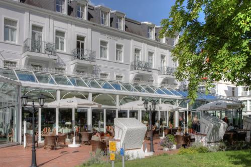 ein Hotel mit Tischen und Stühlen vor einem Gebäude in der Unterkunft SEETELHOTEL Pommerscher Hof das Wellnesshotel im Herzen der Kaiserbäder mit direktem Zugang zur Wellnessoase Shehrazade in Heringsdorf