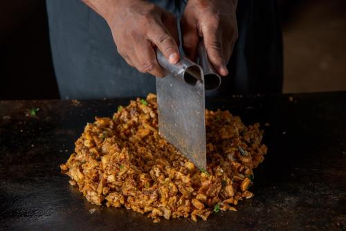 a person cutting up food with a large knife at Hotel Elephant Reach in Yala