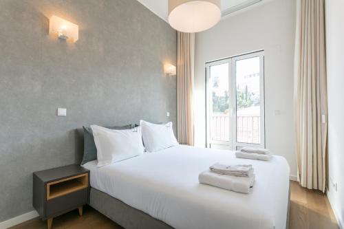 - une chambre avec un grand lit blanc et une fenêtre dans l'établissement FLH Restauradores Modern Apartment, à Lisbonne