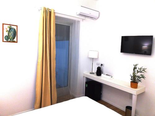 1 dormitorio con 1 cama y escritorio con TV en B&B Suites Via del Mare, en Presicce