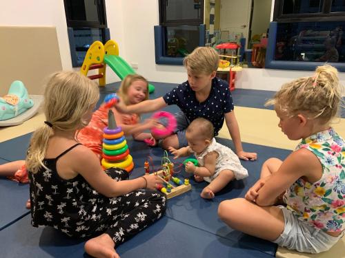 un grupo de niños sentados en el suelo con un bebé en The Seens Hotel, en Krabi