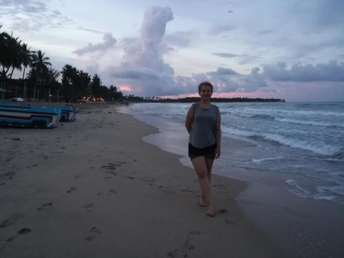 a woman standing on the beach at sunset at Lobster Inn in Trincomalee