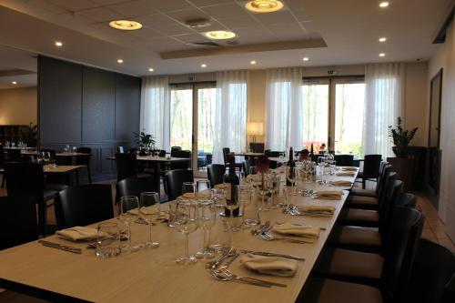 a long table in a restaurant with glasses on it at Logis Le Quai Fleuri in Voves