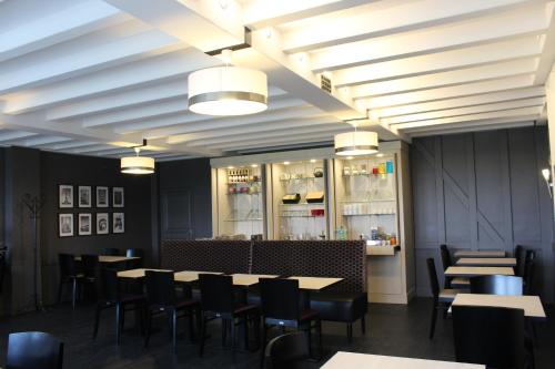 Un comedor con mesas, sillas y luces. en Logis Hôtel Restaurant Le Quai Fleuri, en Voves