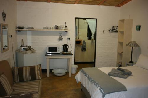 a bedroom with a bed and a desk with a laptop at And the cow jumped over the moon... in Nieu-Bethesda