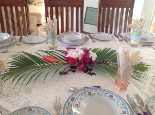 a table with plates and flowers on top of it at Fayruz Villa is a 3 bedroom, 3 bathroom detached house with AC and swimming pool 5 minutes walk from Flic en Flac public beach in Flic-en-Flac