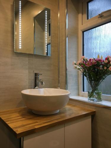 a bathroom with a sink and a vase of flowers at Treetops Bungalow Loch Ness in Drumnadrochit