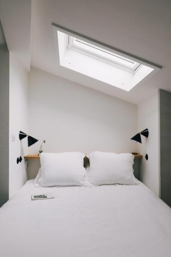 a bedroom with a large white bed with a skylight at Inferniño Apartments in Santiago de Compostela