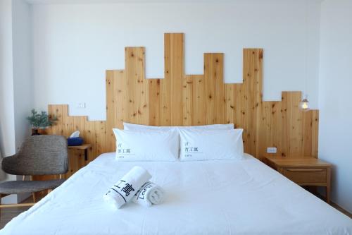 a bedroom with a large white bed with a wooden headboard at Lof/it in Taitung City
