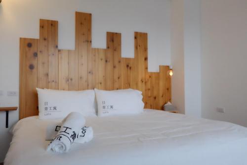a bedroom with a white bed with a wooden headboard at Lof/it in Taitung City