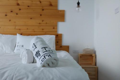 a bedroom with a bed with white sheets and pillows at Lof/it in Taitung City