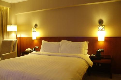 a large bed in a hotel room with two lights at Grand Noble Hotel Xi’an in Xi'an