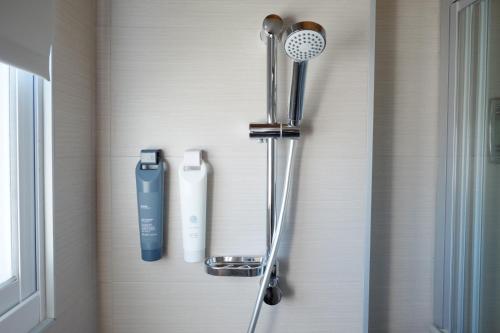 a shower head and a hair dryer on a wall at Lof/it in Taitung City