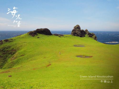 a green hill with rocks on top of it at Waiting Here B&B in Green Island