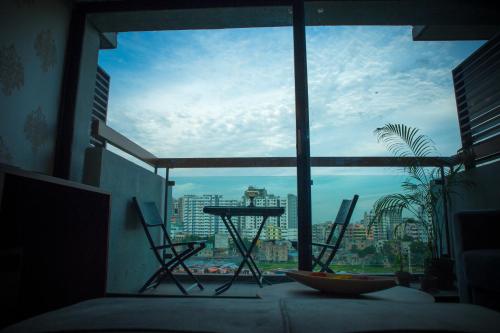 een kamer met een groot raam met een tafel en stoelen bij Coventina Lake Suites in Dhaka