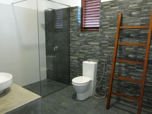 a bathroom with a toilet and a glass shower at Villa Beach Road Ambalangoda in Ambalangoda
