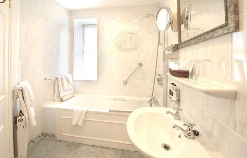 a white bathroom with a tub and a sink at The Old Bank Town House in Kinsale