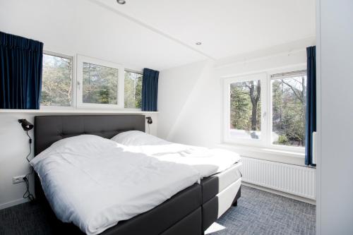 a bedroom with a bed with white sheets and windows at Bok's Bungalowpark in Garderen