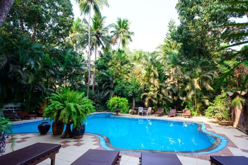 a swimming pool in a resort with palm trees at Bellflower Alidia Beach Resort in Baga