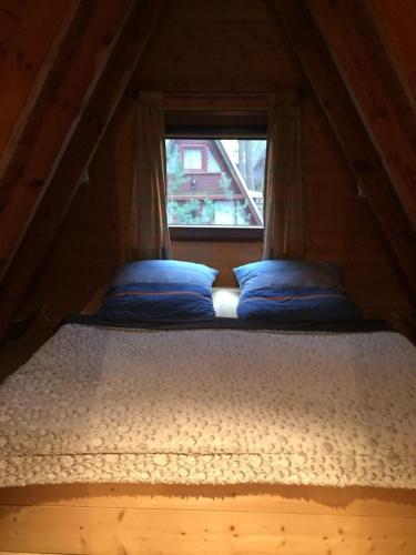 a bed in a small room with a window at Domek Letniskowy in Mrzeżyno