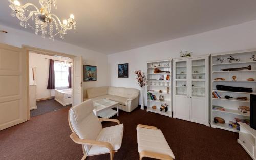 a living room with white furniture and a chandelier at Apartmány Tábor in Tábor