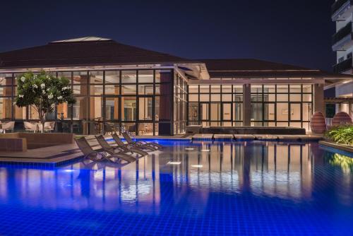 a swimming pool with chairs in front of a building at dusitD2 Davao in Davao City